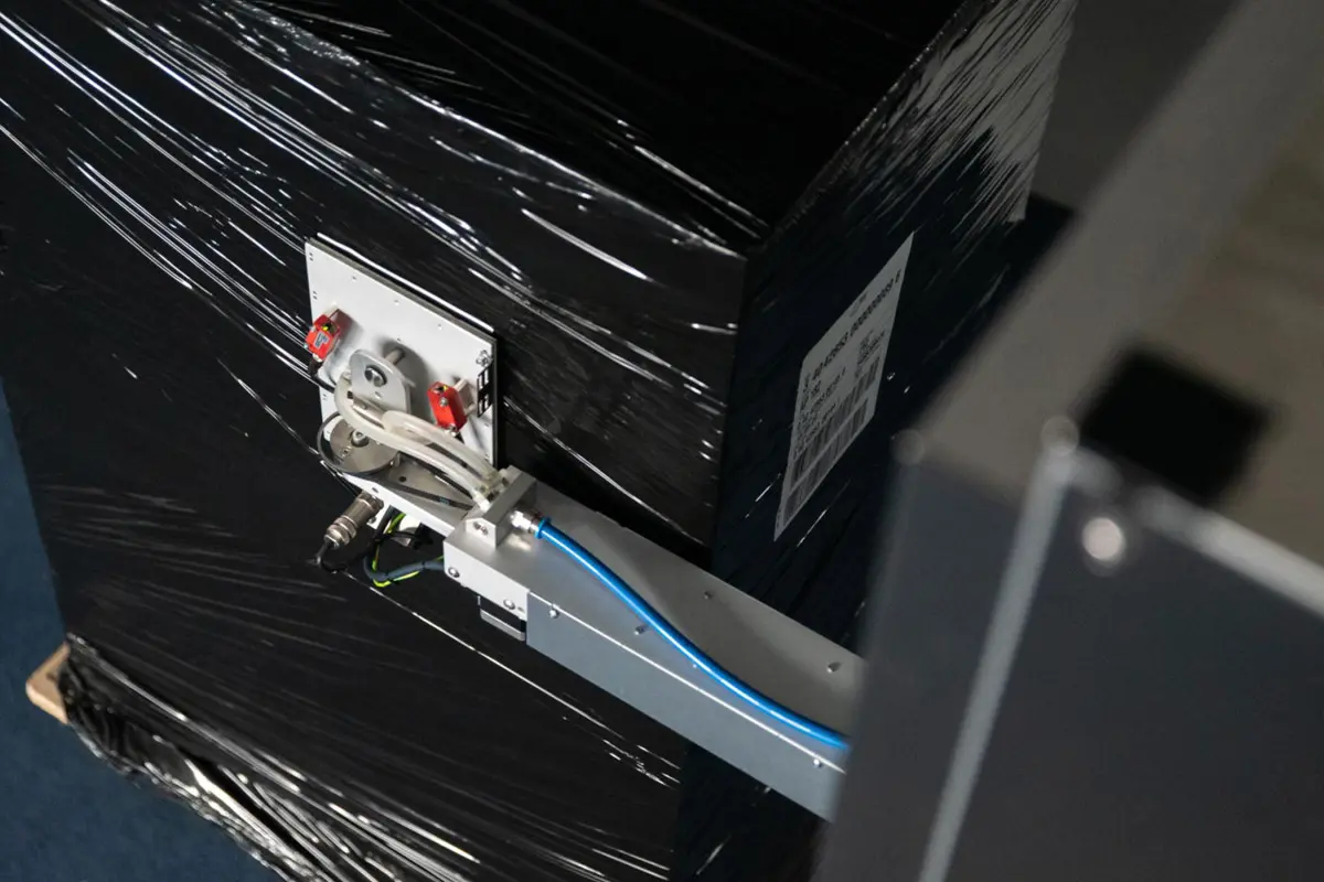 Label applicator applying a shipping label on a shrink-wrapped pallet